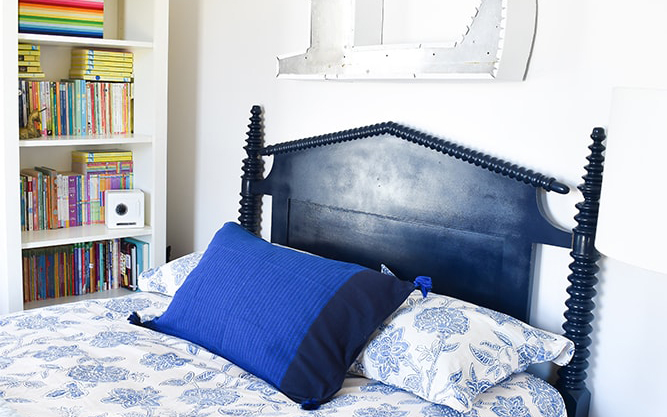Navy blue headboard behind a bed in a girl’s bedroom.