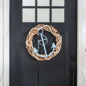 A wooden wreath with a light blue anchor in the center hanging on a front door.