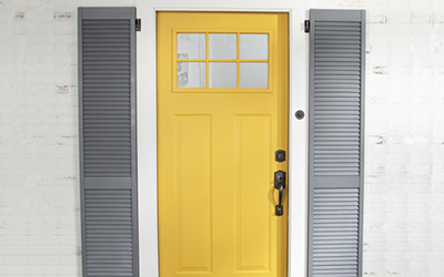 Gray shutters around yellow front door.