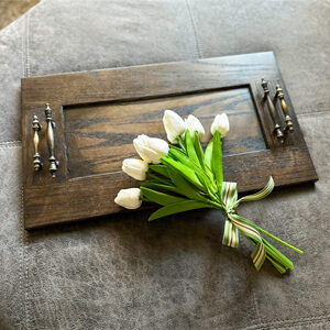 A bouquet of flowers over a wooden ottoman tray.