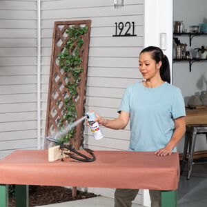 A woman applying light blue spray paint to a metal anchor. 