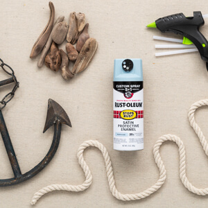 A metal anchor, pieces of driftwood, a hot glue gun, metal wreath frame, length of rope and can of light blue Rust-Oleum Stops Rust with Custom Spray 5-in-1.
